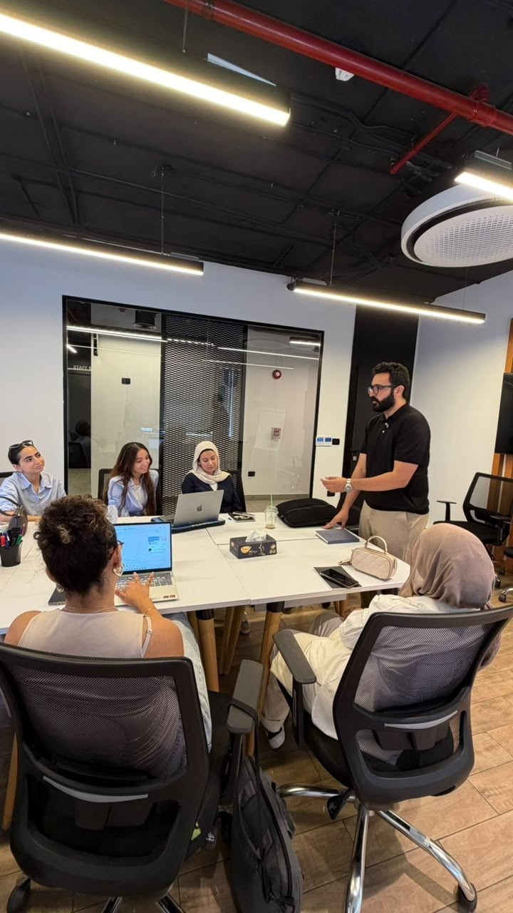 Eslam Toba standing and presenting to a small group around an office table