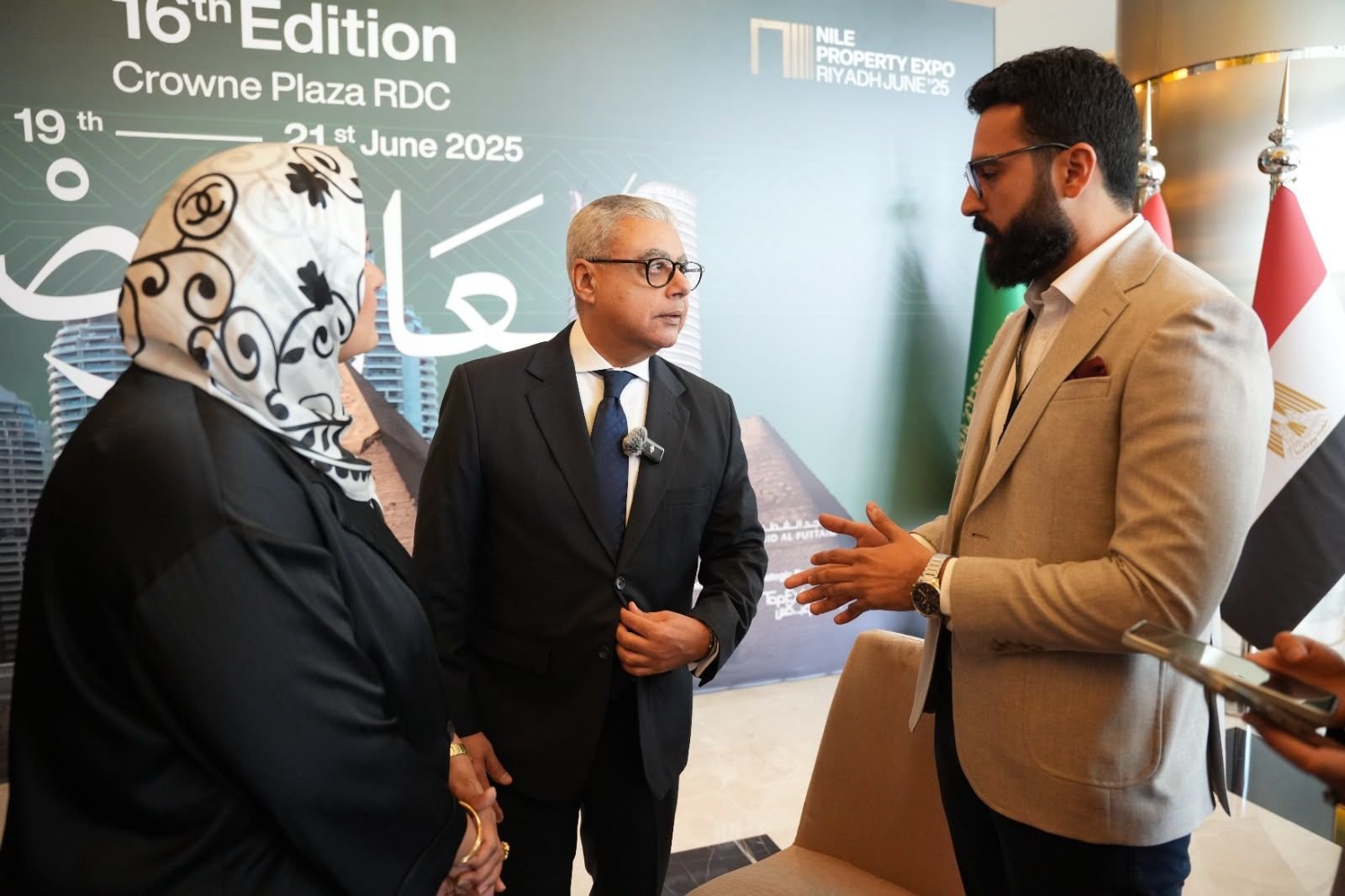 Eslam in a suit in conversation with a senior guest at the Nile Property Expo in Riyadh